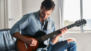 homem sentado aprendendo a tocar guitarra